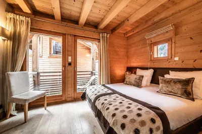 a bedroom with a bed and a chair in a cabin at Chalet Inari Chamonix - by EMERALD STAY in Chamonix-Mont-Blanc