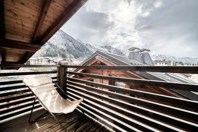 a chair on a balcony with a view of mountains at Chalet Inari Chamonix - by EMERALD STAY in Chamonix-Mont-Blanc