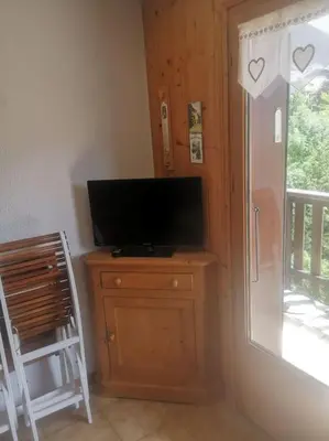 a television sitting on a wooden dresser next to a window at Studio cabine 4 personnes, votre refuge montagnard in Saint-Gervais-les-Bains