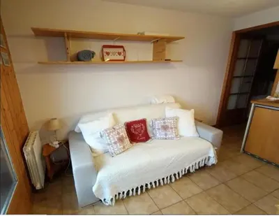 a living room with a white couch with pillows at Studio cabine 4 personnes, votre refuge montagnard in Saint-Gervais-les-Bains