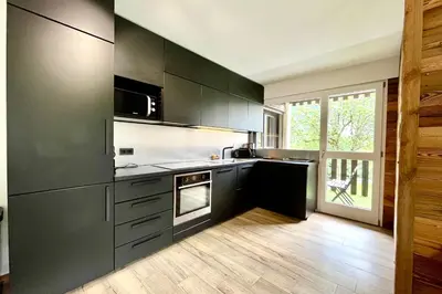 a kitchen with black cabinets and a large window at Le Refuge Diorama in Saint-Gervais-les-Bains