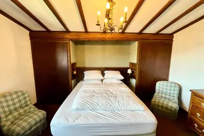 a bed in a room with two chairs and a chandelier at L’Héritage Régence in Megève