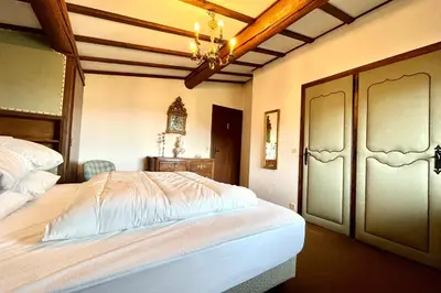 a bedroom with a large bed and a chandelier at L’Héritage Régence in Megève