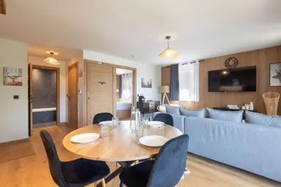 a living room with a table and a blue couch at L'Altima Megève - Eclat des Veriaz in Megève