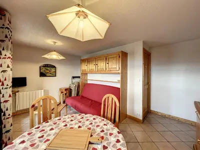 a living room with a red couch and a table at Charmant 3 pièces avec jardin, parking et proximité ski bus à 900m du village de Combloux - FR-1-560-121 in Combloux