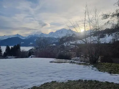 a snow covered hill with the sun in the background at Charmant 3 pièces avec jardin, parking et proximité ski bus à 900m du village de Combloux - FR-1-560-121 in Combloux