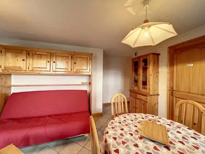 a room with a red bed and a table and cabinets at Charmant 3 pièces avec jardin, parking et proximité ski bus à 900m du village de Combloux - FR-1-560-121 in Combloux