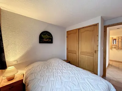 a bedroom with a white bed and a wooden door at Charmant 3 pièces avec jardin, parking et proximité ski bus à 900m du village de Combloux - FR-1-560-121 in Combloux
