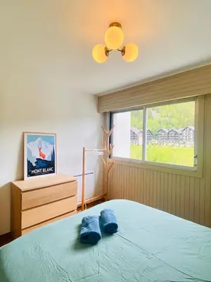 a bedroom with a bed with two blue towels on it at Pied des pistes/Hyper centre/Balcon/Parking in Chamonix-Mont-Blanc