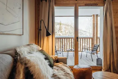 a living room with a couch and a sliding glass door at Le Cocon Blanc - Appartement « cosy & chic » in Megève