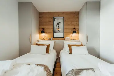 two beds in a room with wooden walls at Le Cocon Blanc - Appartement « cosy & chic » in Megève
