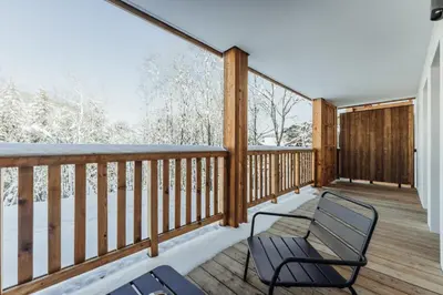 a deck with two chairs and snow covered trees at Le Cocon Blanc - Appartement « cosy & chic » in Megève