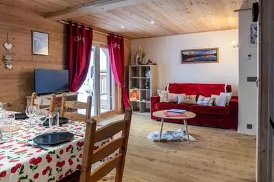 a living room with a table and a red couch at Charmant appartement dans chalet, coeur de Megève in Megève