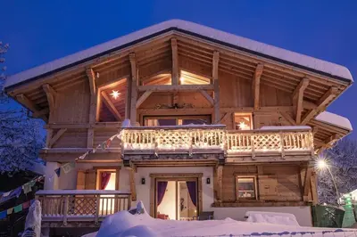 a log cabin in the snow at night at Charmant appartement dans chalet, coeur de Megève in Megève