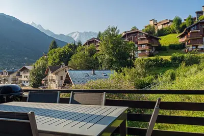 a wooden table and chairs on a balcony with mountains at Chalet La Cordée, 160m2, 4 chambres, sauna in Saint-Gervais-les-Bains