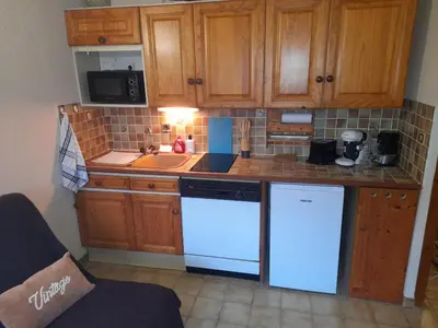 a kitchen with white appliances and wooden cabinets at Le chalet des neiges 3 est au calme situé à 5 mn à pied du centre juste à côté du terrain de foot est composé canapé convertible et 3 lits supperposés parking privé sur place et arrêt navette gratuite à 30 m in Les Carroz d'Araches