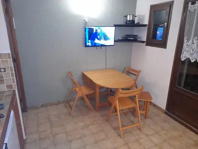 a dining room table and chairs with a television on the wall at Le chalet des neiges 3 est au calme situé à 5 mn à pied du centre juste à côté du terrain de foot est composé canapé convertible et 3 lits supperposés parking privé sur place et arrêt navette gratuite à 30 m in Les Carroz d'Araches