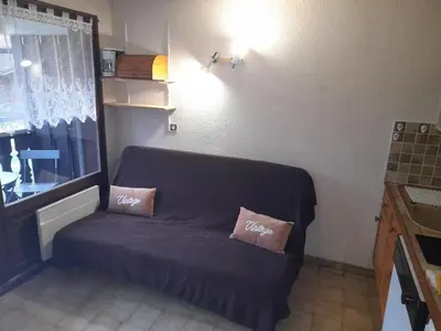 a couch in a room with two pillows on it at Le chalet des neiges 3 est au calme situé à 5 mn à pied du centre juste à côté du terrain de foot est composé canapé convertible et 3 lits supperposés parking privé sur place et arrêt navette gratuite à 30 m in Les Carroz d'Araches