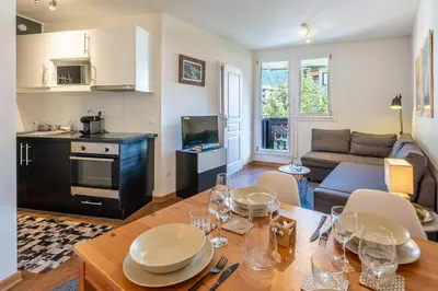 a kitchen and a living room with a table and chairs at Le Balcon du Brevent - Central - Vue montagne in Chamonix-Mont-Blanc