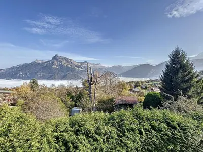 a house on a hill with mountains in the background at Studio mezzanine au centre de Combloux avec parking - FR-1-560-123 in Combloux