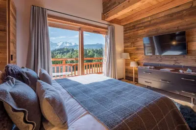 a bedroom with a bed and a large window at Chalet 14 personnes I Luxe I Piscine & Sauna I Salle cinéma I Le Chalet Club in Combloux
