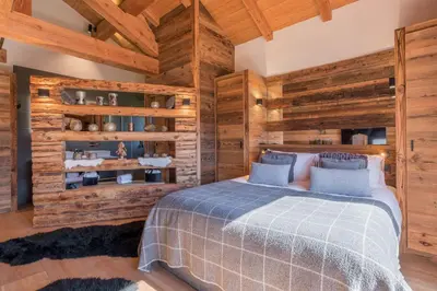 a bedroom with a bed and wooden walls at Chalet 14 personnes I Luxe I Piscine & Sauna I Salle cinéma I Le Chalet Club in Combloux