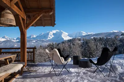a porch with chairs and snow covered mountains at Chalet 14 personnes I Luxe I Piscine & Sauna I Salle cinéma I Le Chalet Club in Combloux