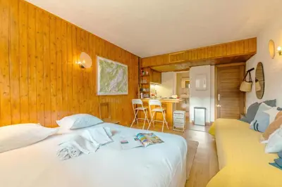a bedroom with a white bed and a yellow couch at Studio de Balme - Happy Rentals in Chamonix-Mont-Blanc