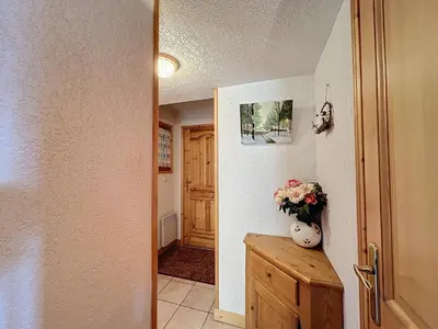 a hallway with a door and a vase of flowers on a table at Appartement avec garage proches ski bus à Combloux - FR-1-560-126 in Combloux
