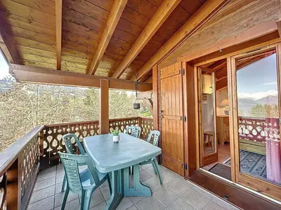 a wooden deck with a table and chairs on it at Appartement avec garage proches ski bus à Combloux - FR-1-560-126 in Combloux