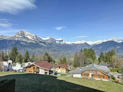 a house on a hill with mountains in the background at Appartement avec garage proches ski bus à Combloux - FR-1-560-126 in Combloux