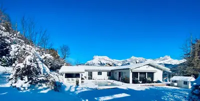 a house with snow covered mountains in the background at Chalet Soleil Blanc au pied des pistes in Saint-Gervais-les-Bains