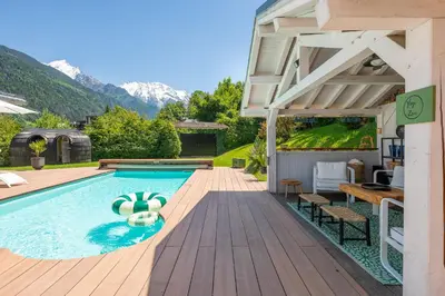 a swimming pool with a wooden deck and a house at Chalet Soleil Blanc au pied des pistes in Saint-Gervais-les-Bains