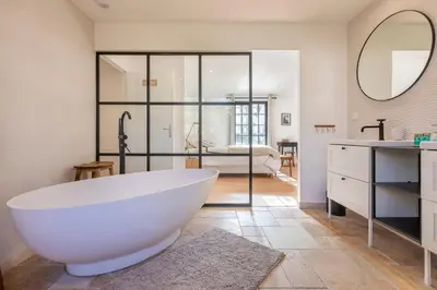 a bathroom with a large white tub and a bedroom at Chalet Soleil Blanc au pied des pistes in Saint-Gervais-les-Bains