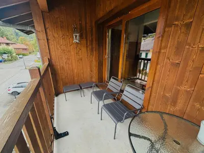 a balcony with chairs and a table and a barn at Confortable Appartement T3 au Centre avec Animaux admis - FR-1-624-158 in Samoëns