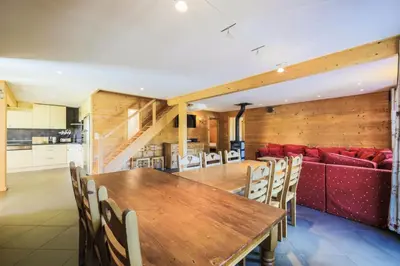 a dining room with a wooden table and a red couch at Les Chalets de Flaine Hameau - maeva Home - Chalet 7 Pièces 12 Personnes - Prestige MAE-3379 in Flaine