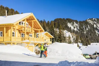 two people standing in the snow in front of a house at Les Chalets de Flaine Hameau - maeva Home - Chalet 3 Pièces 8 Personnes - Confort MAE-3392 in Flaine