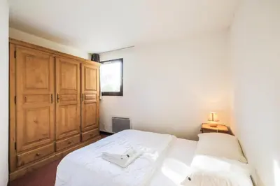 a bedroom with a white bed and a wooden cabinet at Résidence Pégase - maeva Home - Appartement 3 pièces 8 personnes Confort MAE-3481 in Flaine