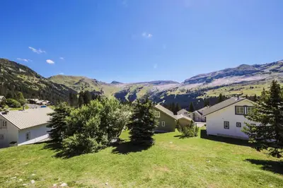 a house with a yard with mountains in the background at Les Chalets de Flaine Hameau - maeva Home - Chalet 3 Pièces 8 Personnes - Confort MAE-3654 in Flaine