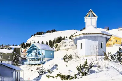a church in the snow next to a mountain at Les Chalets de Flaine Hameau - maeva Home - Chalet 7 Pièces 12 Personnes - Sélection MAE-3656 in Flaine