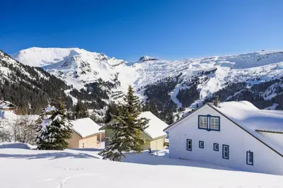 a white house in the snow with mountains in the background at Les Chalets de Flaine Hameau - maeva Home - Chalet 5 Pièces 8 Personnes - Confort MAE-3661 in Flaine