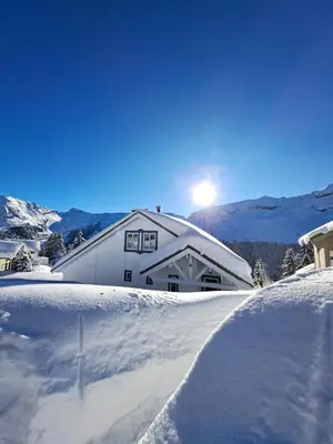 a house covered in snow with the sun behind it at Les Chalets de Flaine Hameau - maeva Home - Chalet 5 Pièces 8 Personnes - Confort MAE-3661 in Flaine