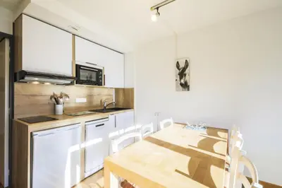 a kitchen with a wooden table and white cabinets at Résidence Castor - maeva Home - Appartement 2 Pièces 6 Personnes - Confort MAE-3847 in Arâches-la-Frasse