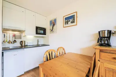 a kitchen with a wooden table and a kitchen with white cabinets at Résidence Sirius - maeva Home - Studio 4 Personnes - Confort MAE-3896 in Arâches-la-Frasse