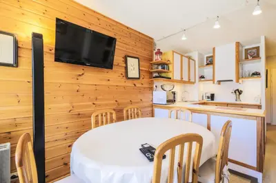 a kitchen with a table and a tv on a wooden wall at Résidence Le Château de Crans - maeva Home - Appartement 2 Pièces 6 Personnes - Prestige MAE-4253 in Flaine