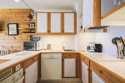a kitchen with wooden cabinets and white appliances at Résidence Le Château de Crans - maeva Home - Appartement 2 Pièces 6 Personnes - Prestige MAE-4253 in Flaine