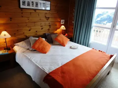 a bedroom with a large bed with a wooden wall at Résidence Le Château de Crans - maeva Home - Appartement 2 Pièces 6 Personnes - Prestige MAE-4253 in Flaine