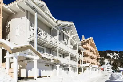 a large white building with snow on the ground at Résidence Le Château de Crans - maeva Home - Appartement 5 pièces 10 personnes avec sauna privé - Prestige MAE-4441 in Flaine