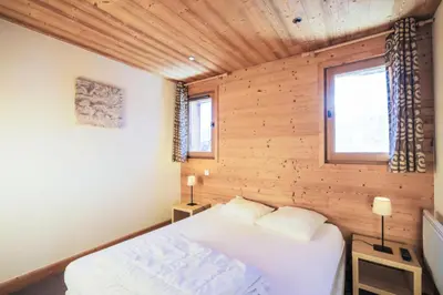 a bedroom with a bed and two windows at Résidence Refuge du Golf - maeva Home - Appartement 4 Pièces 8 Personnes - Prestige MAE-5505 in Arâches-la-Frasse