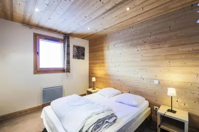 a bedroom with a wooden wall with a bed and a window at Résidence Refuge du Golf - maeva Home - Appartement 4 Pièces 8 Personnes - Prestige MAE-5505 in Arâches-la-Frasse